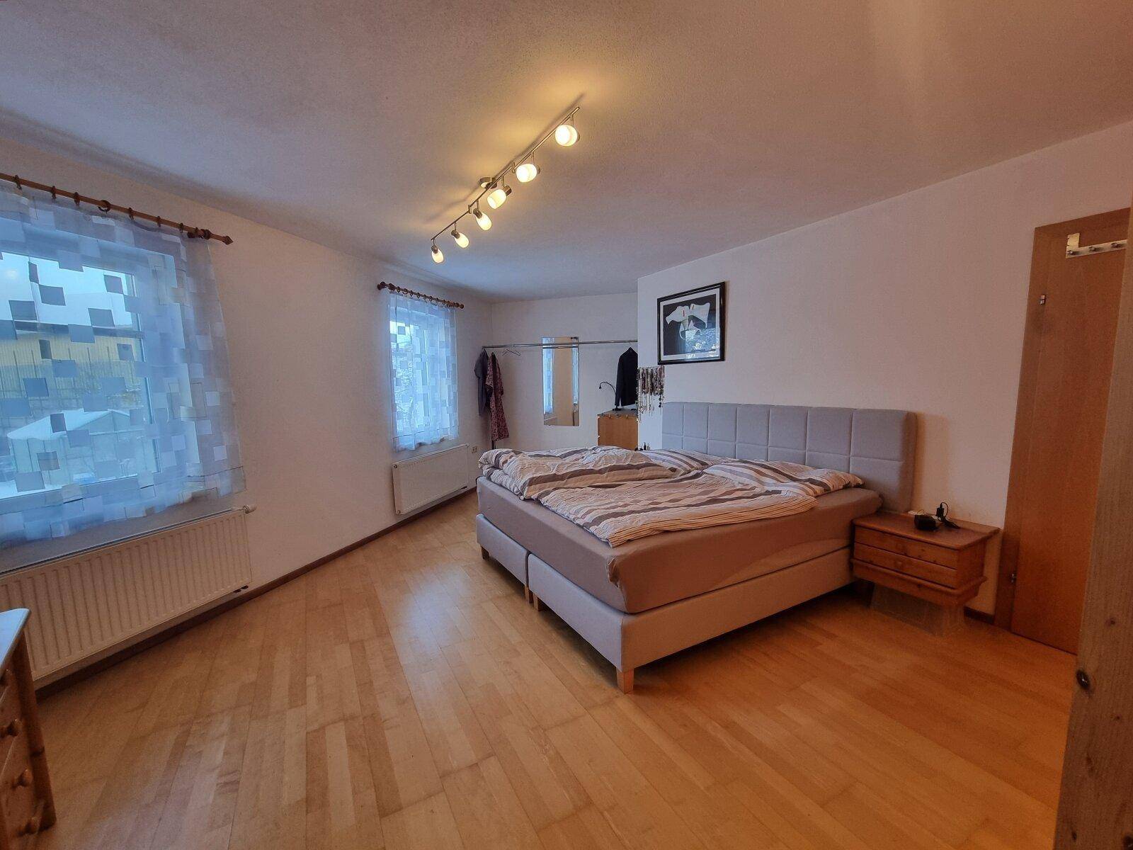 Schlafzimmer mit Doppelbett, Holzmöbeln und hellem Parkettboden.
