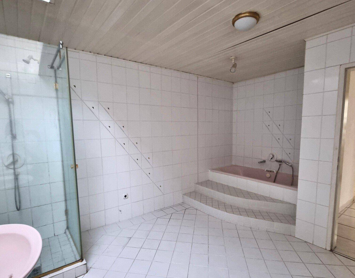 Badezimmer mit eingebauter Eckbadewanne mit Stufen und einer separaten Duschkabine.