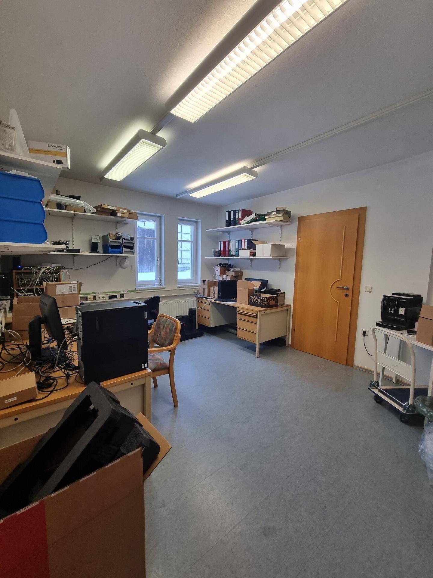 Büro mit Regalen, Schreibtischen und Fenster, ideal für Home-Office oder Lagerung.