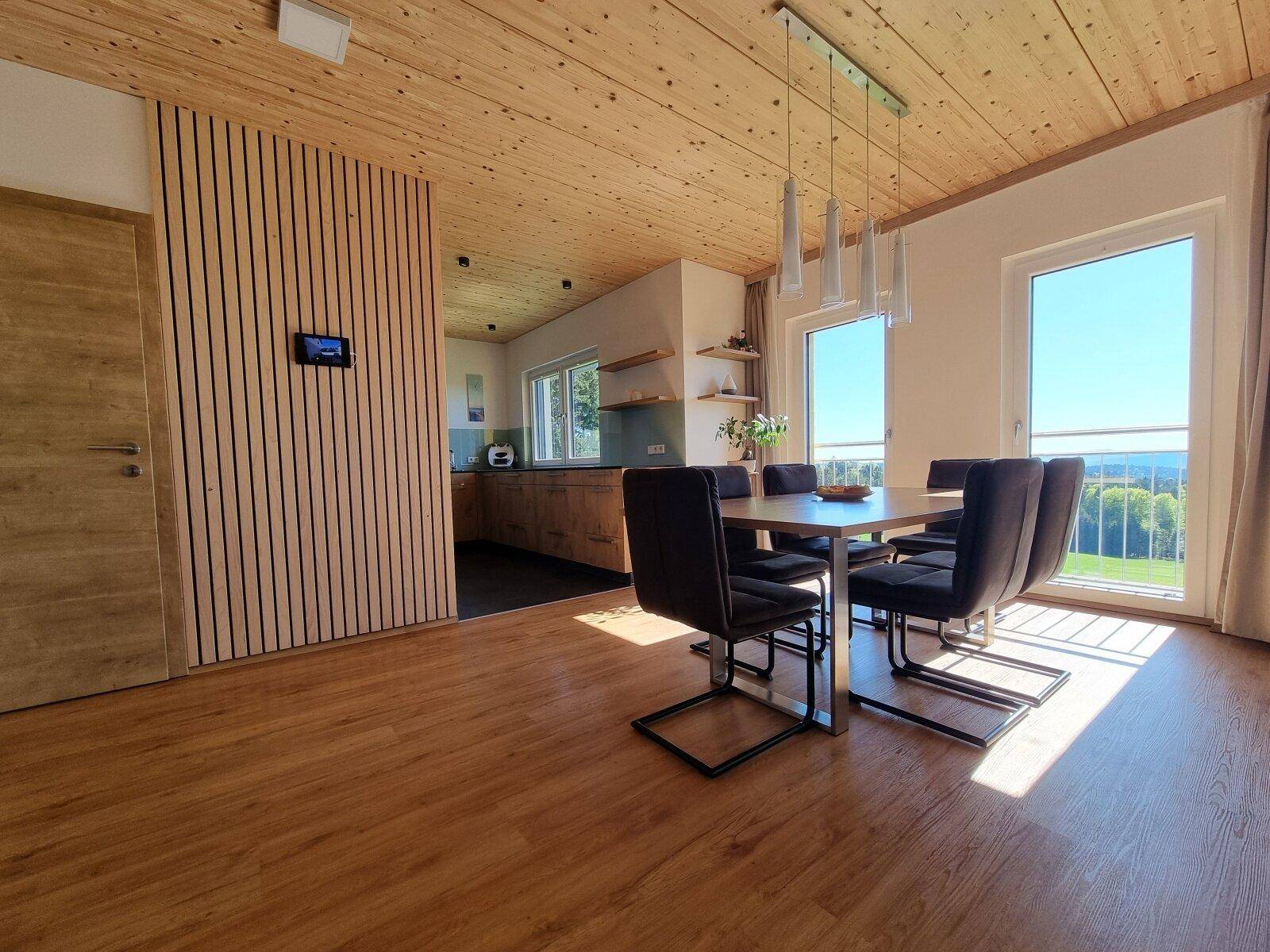 Lichtdurchfluteter Essbereich mit Holzboden, Holzdecke und weitem Ausblick in die Landschaft.
