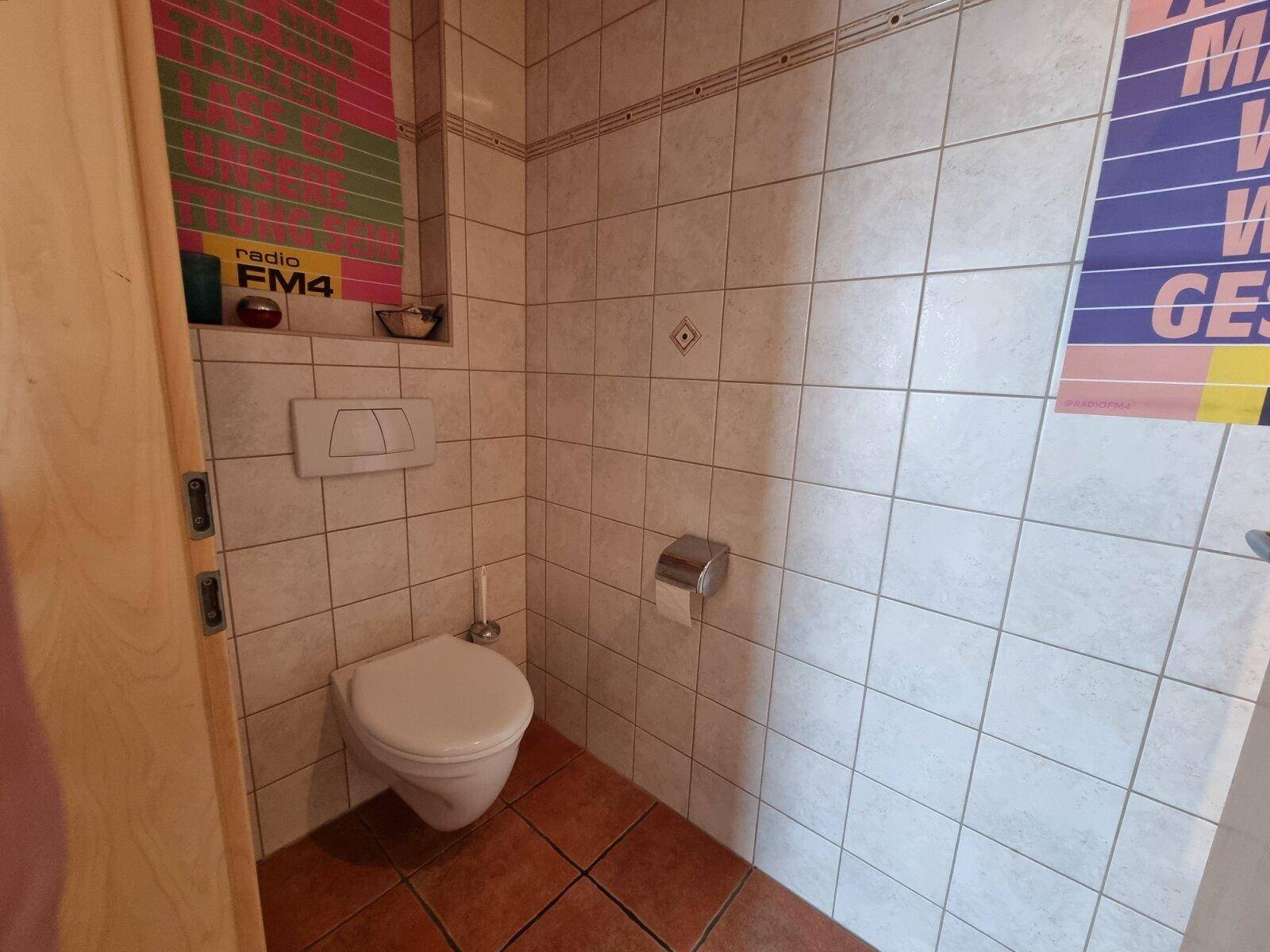 Kleines Gäste-WC mit Fliesenboden und Wand-WC in schlichtem Design.