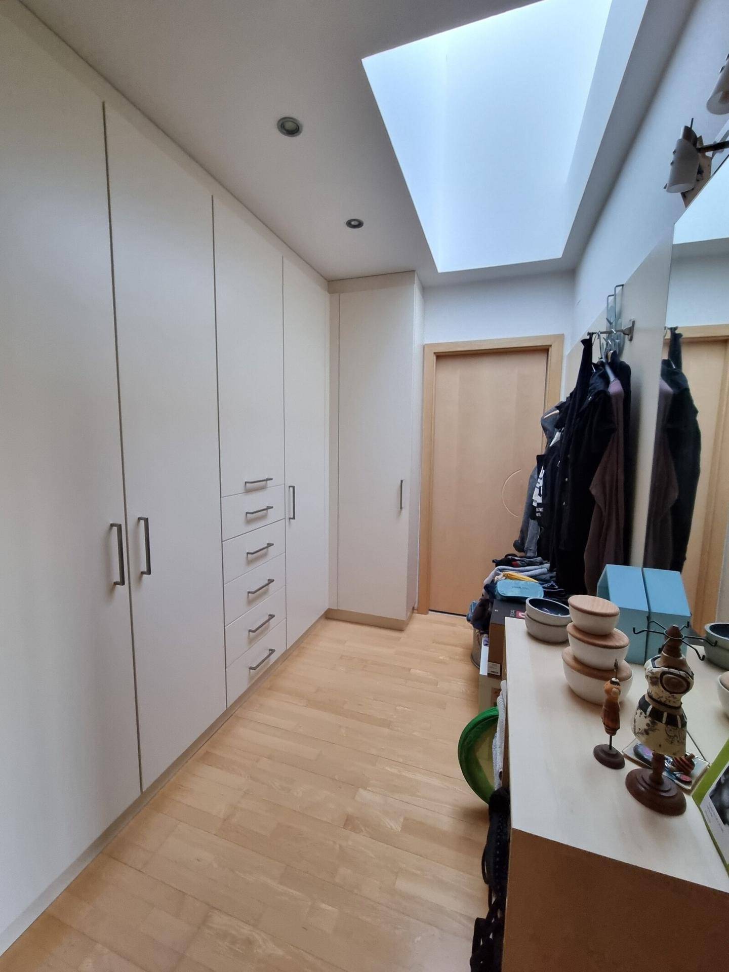 Heller Flur mit Einbauschränken, Holzfußboden und Dachfenster für natürliches Licht.