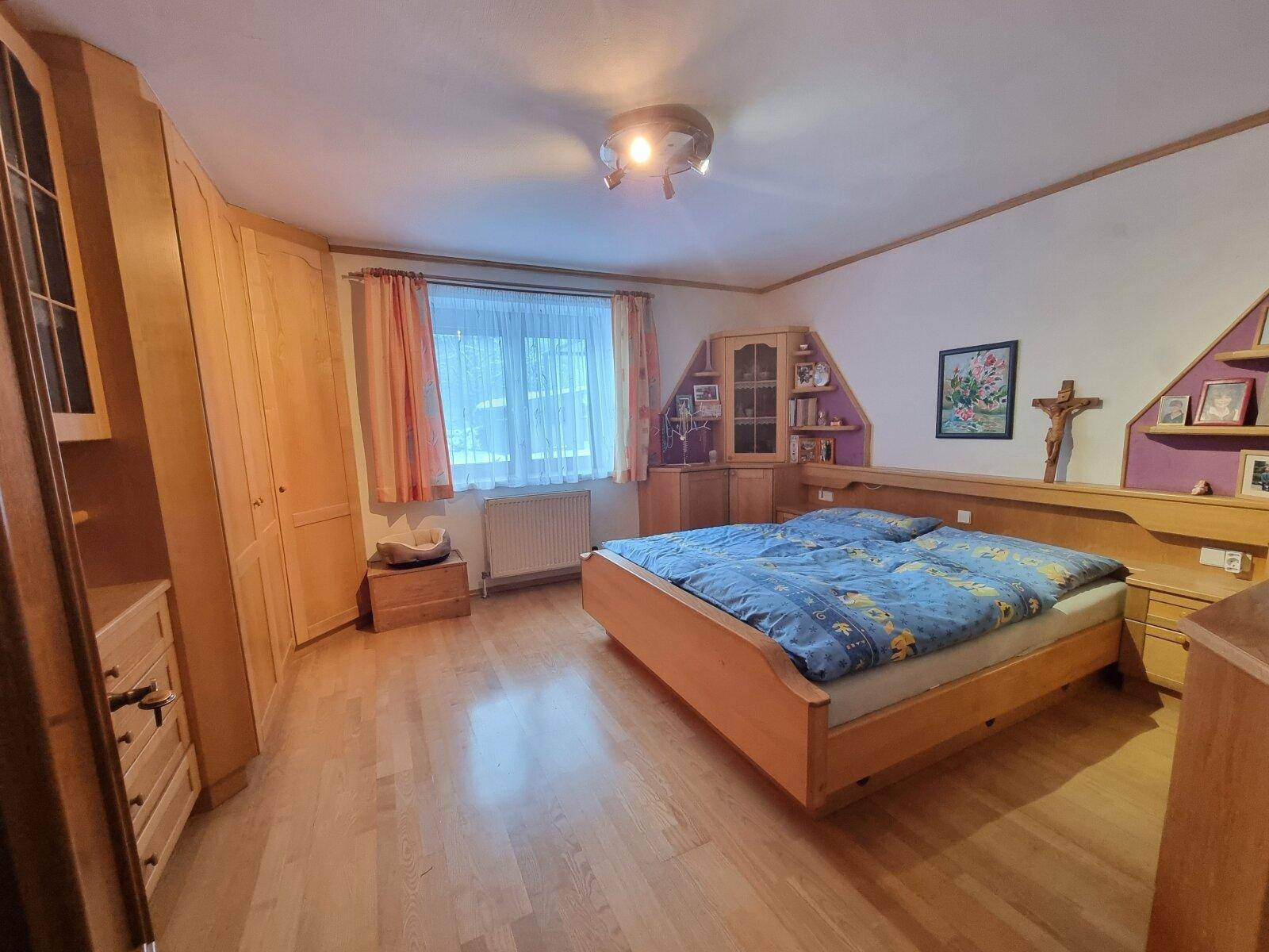 Gemütliches Schlafzimmer mit Holzmöbeln, Doppelbett und Laminatboden.