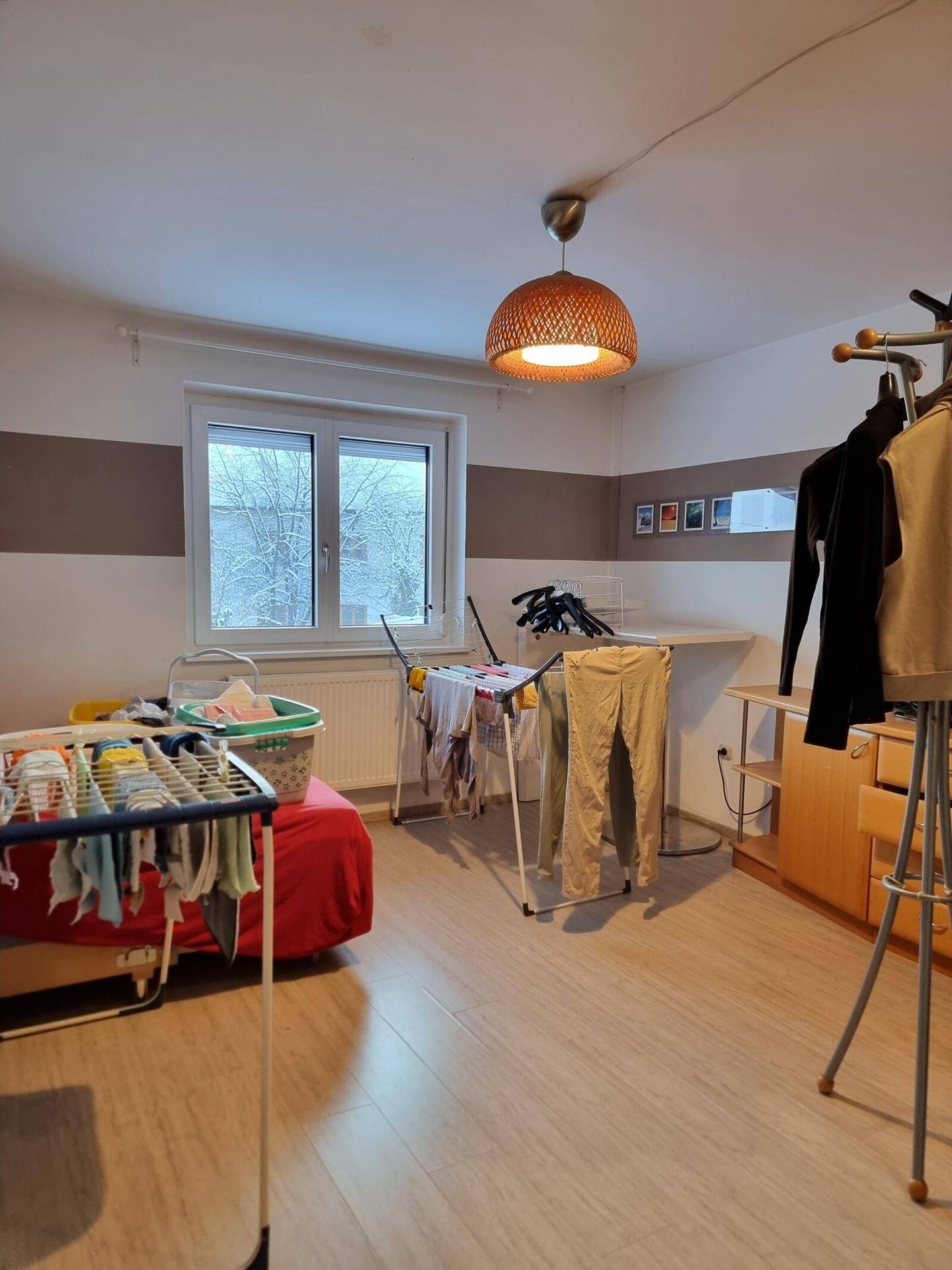 Praktischer Hauswirtschaftsraum mit Wäscheständern, Fenster und Laminatboden.