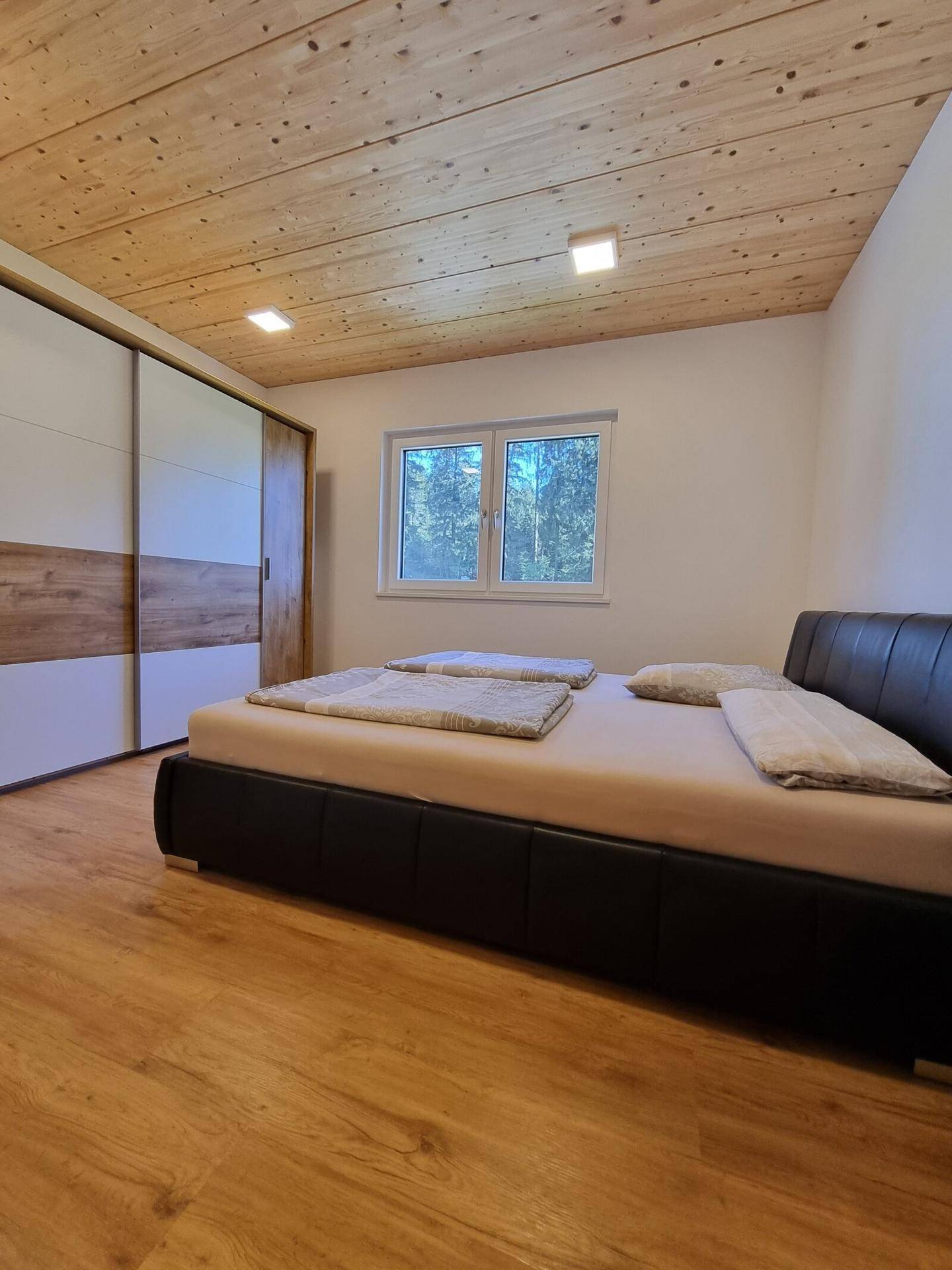 Gemütliches Schlafzimmer mit Holzboden, Holzdecke und großem Kleiderschrank.