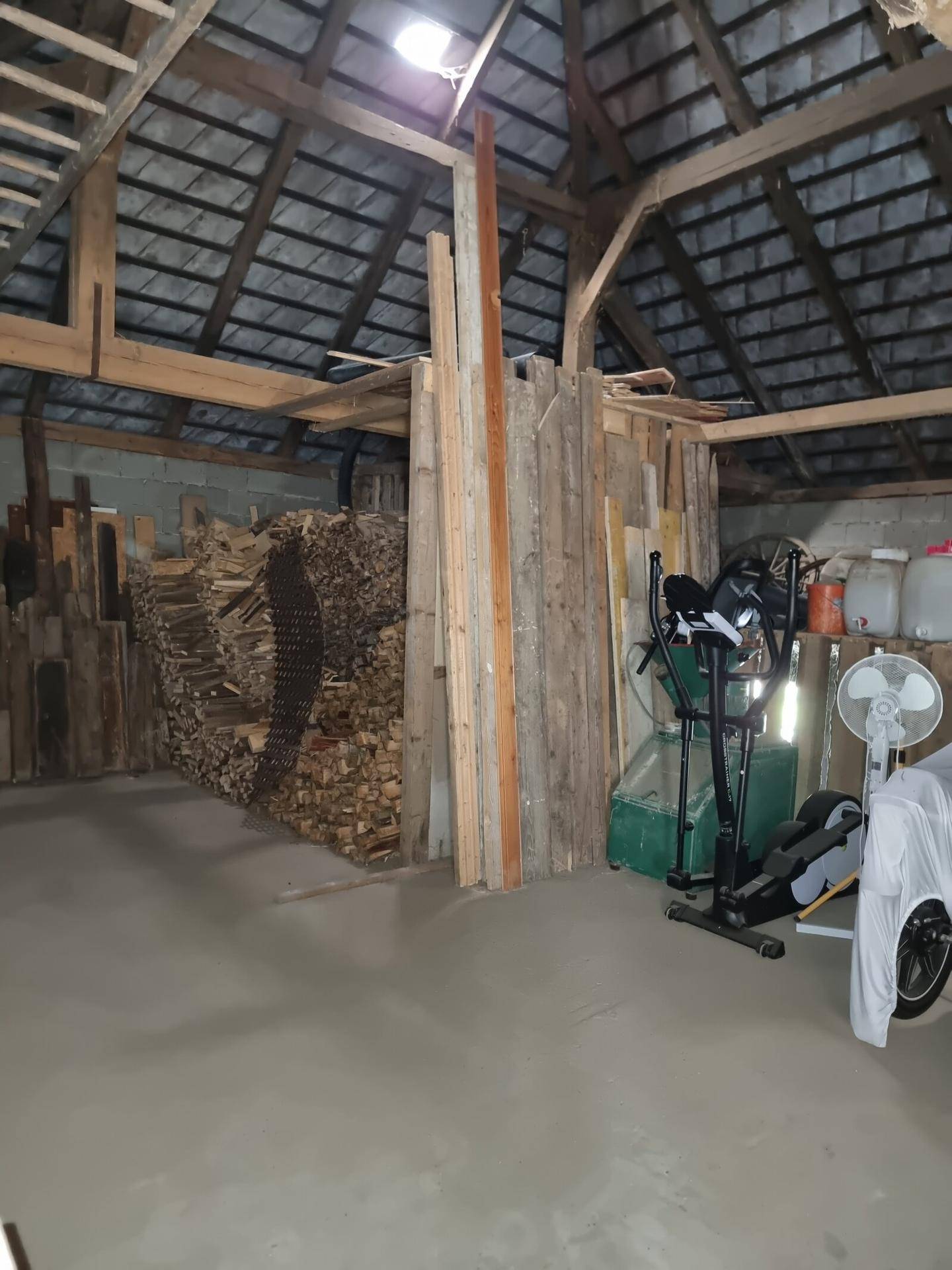 Geräumiger Dachboden mit Holzbalken und Lagerfläche für Brennholz und andere Gegenstände.