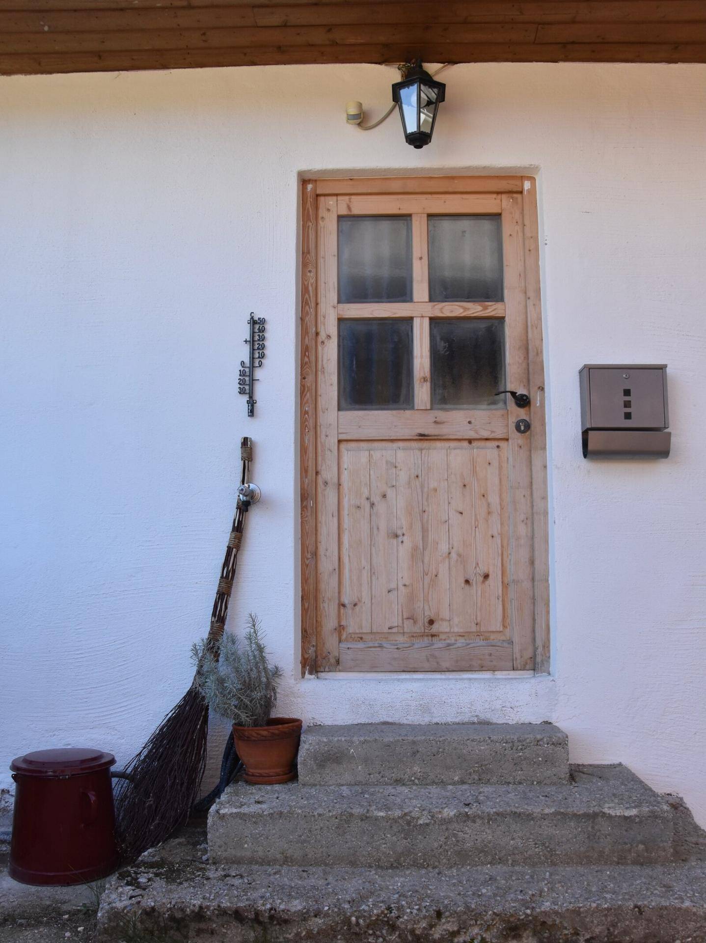 Hölzerne Eingangstür des Hauses mit Stufen und einer traditionellen Laterne darüber.