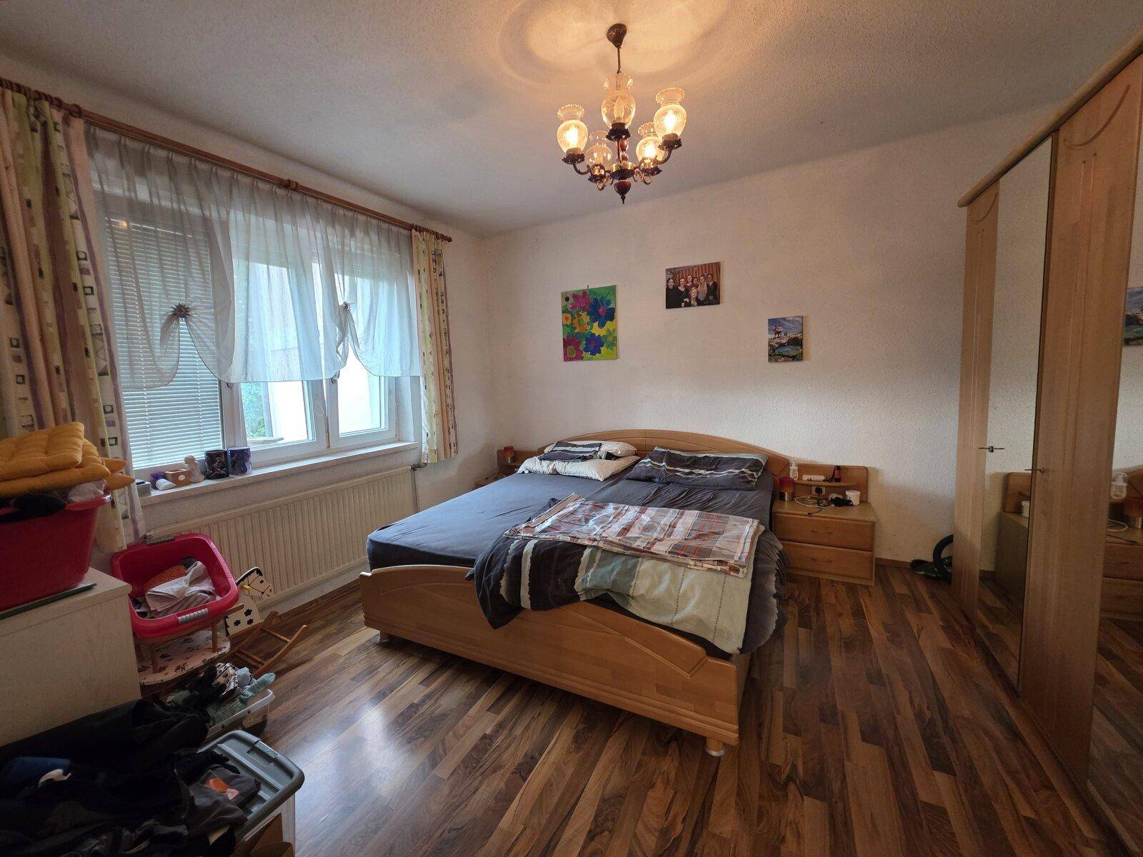 Schlafzimmer mit Doppelbett, Nachttischen, Spiegelschrank und Fenster für natürliches Licht.