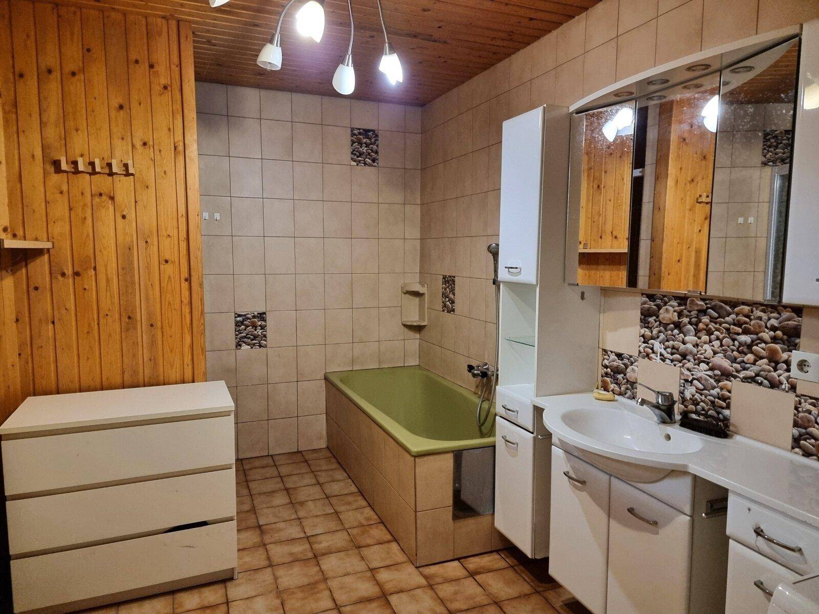 Badezimmer mit Holzvertäfelung, Badewanne und Waschbecken mit Spiegelschrank.