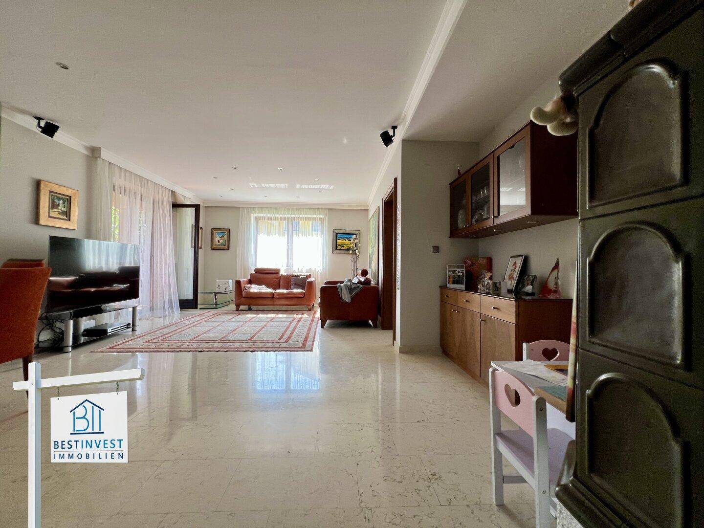 Großzügiges Wohnzimmer mit hellen Fliesenböden, einem großen Teppich und gemütlicher Sofaecke.