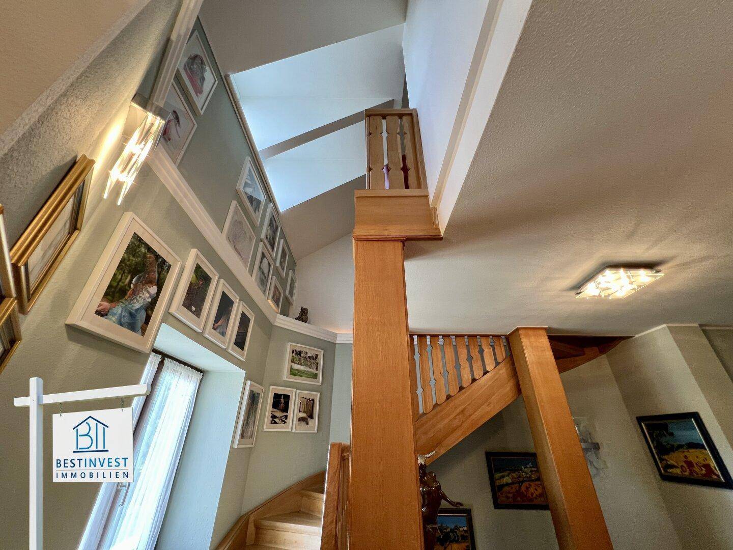 Elegante Holztreppe führt in die obere Etage, geschmückt mit gerahmten Bildern an der Wand.