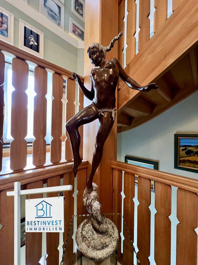 Detailansicht einer Bronzestatue auf dem Holzgeländer der Treppe, ein dekoratives Element.