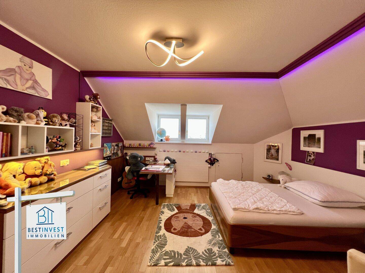 Kinderzimmer mit Schreibtischbereich, Bett und Fenster, unter einer gemütlichen Dachschräge.