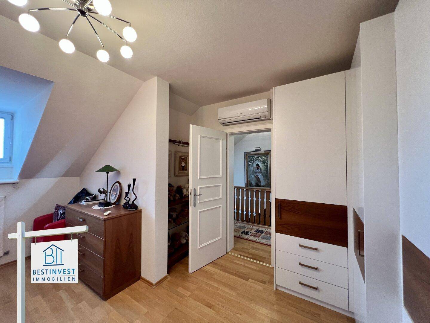 Schlafzimmer mit Kleiderschrank, Holzfußboden und Klimaanlage, mit Zugang zum Flur.