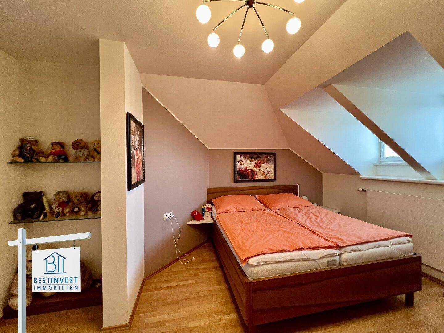 Gemütliches Schlafzimmer mit Bett, Holzfußboden und Dachschräge, ideal für erholsame Nächte.