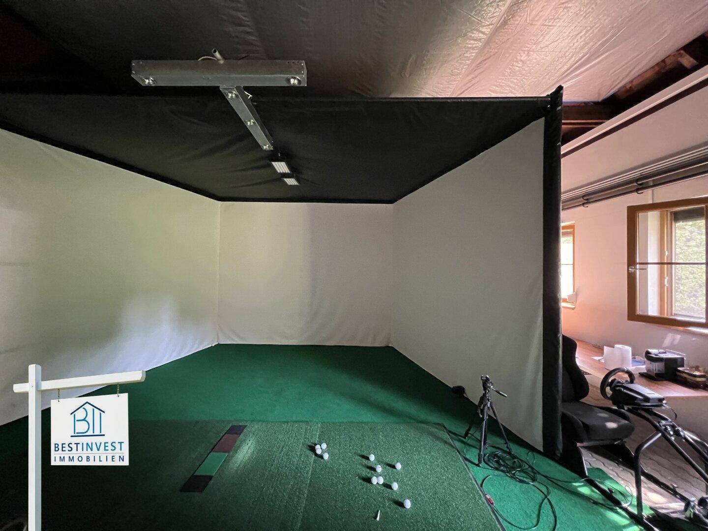 Innenraum mit Golfsimulator und Kunstrasen für sportliche Aktivitäten.
