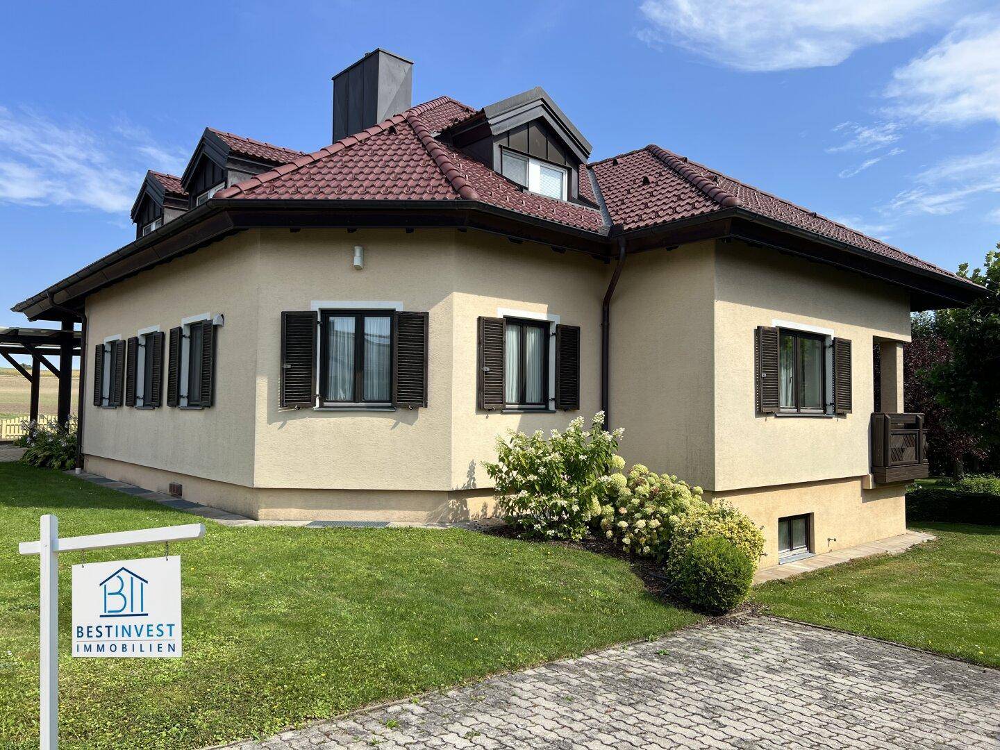Attraktives Einfamilienhaus mit Walmdach, braunen Fensterläden und gepflegter Fassade.