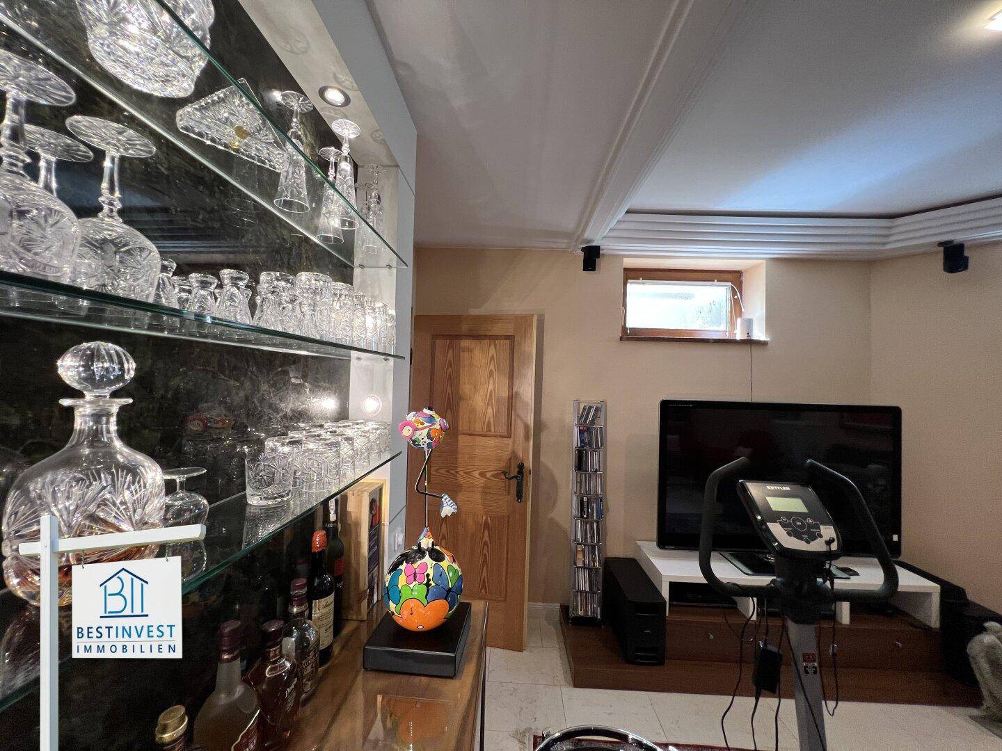 Kellerbereich mit Vitrine für Gläser und Flaschen sowie einem Heimtrainer für sportliche Aktivitäten.