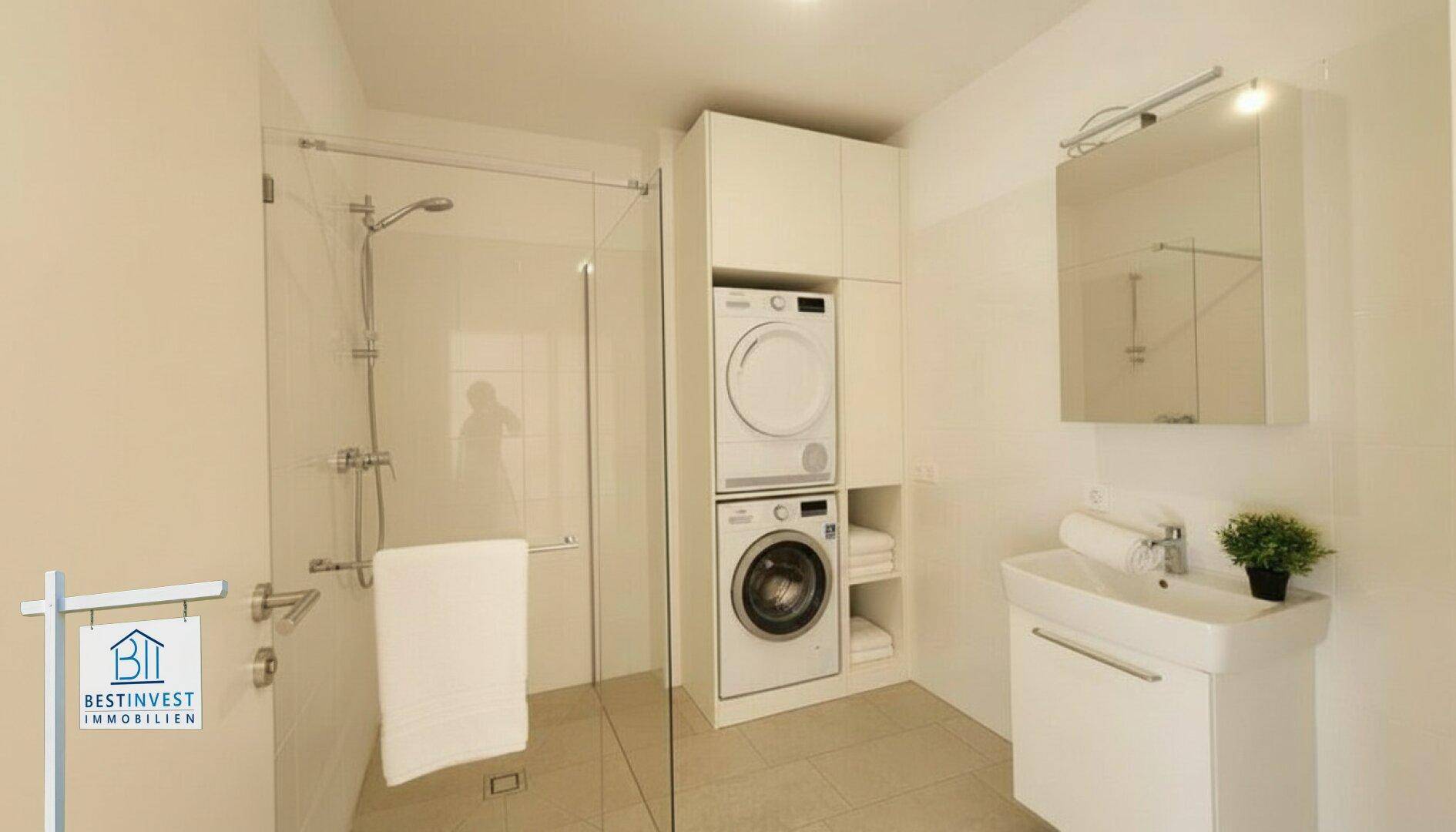 Modernes Badezimmer mit ebenerdiger Dusche, Einzelwaschbecken und Waschmaschine/Trockner.