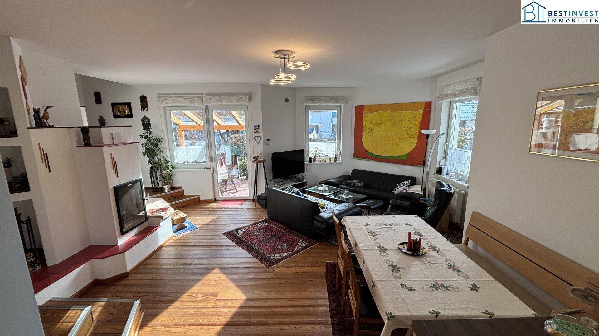 Geräumiger Wohn-Essbereich mit Holzboden, Kamin und Zugang zur Terrasse, hell und einladend.