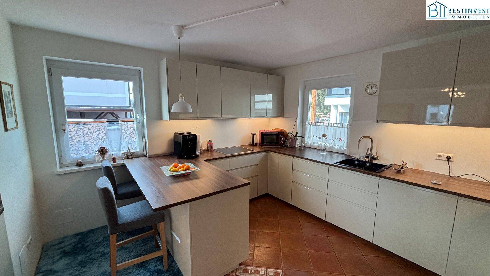 Moderne Küche mit hellen Schränken, Holzarbeitsplatte und integrierter Frühstücksbar.