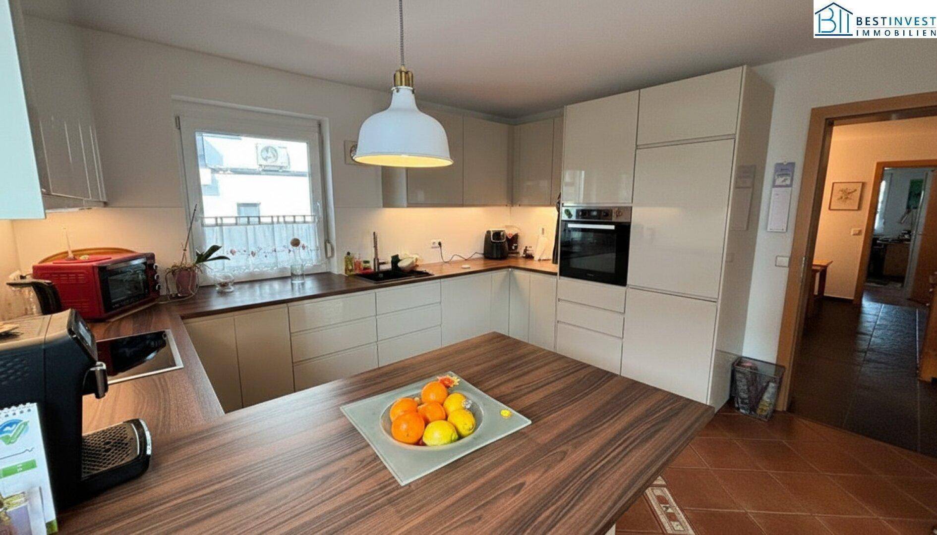 Funktionale Küche mit hellen Fronten, Holzarbeitsplatte und modernen Einbaugeräten.