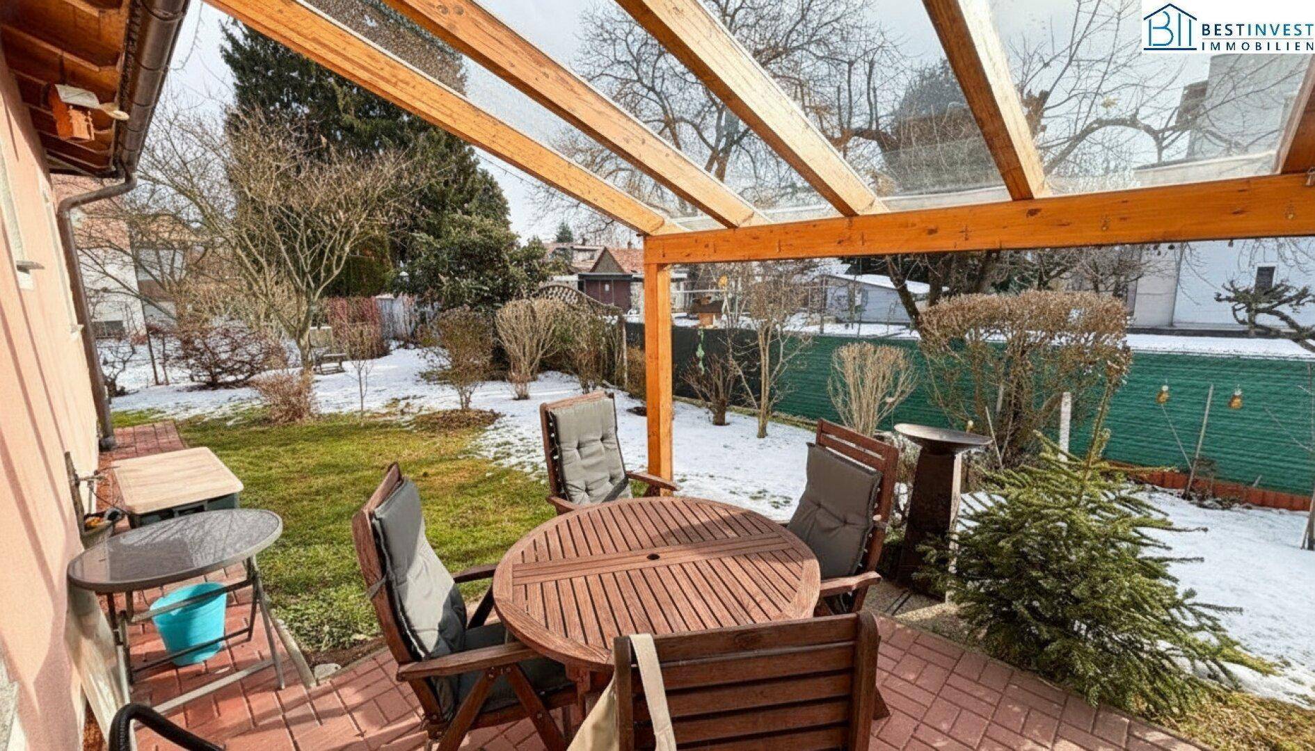 Überdachte Terrasse mit Gartenmöbeln und Blick auf den verschneiten Gartenbereich.