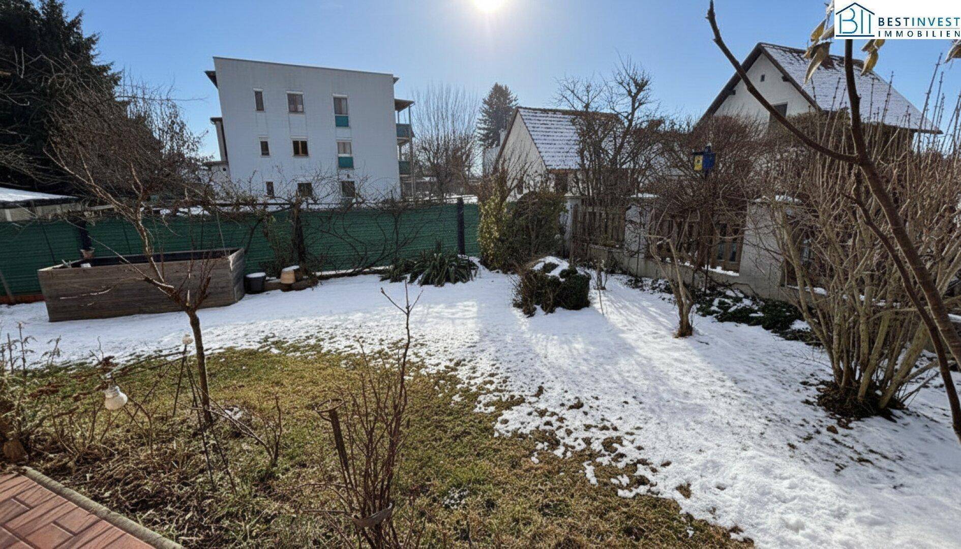 Großer Gartenbereich mit Rasenfläche und Bäumen, teilweise mit Schnee bedeckt.