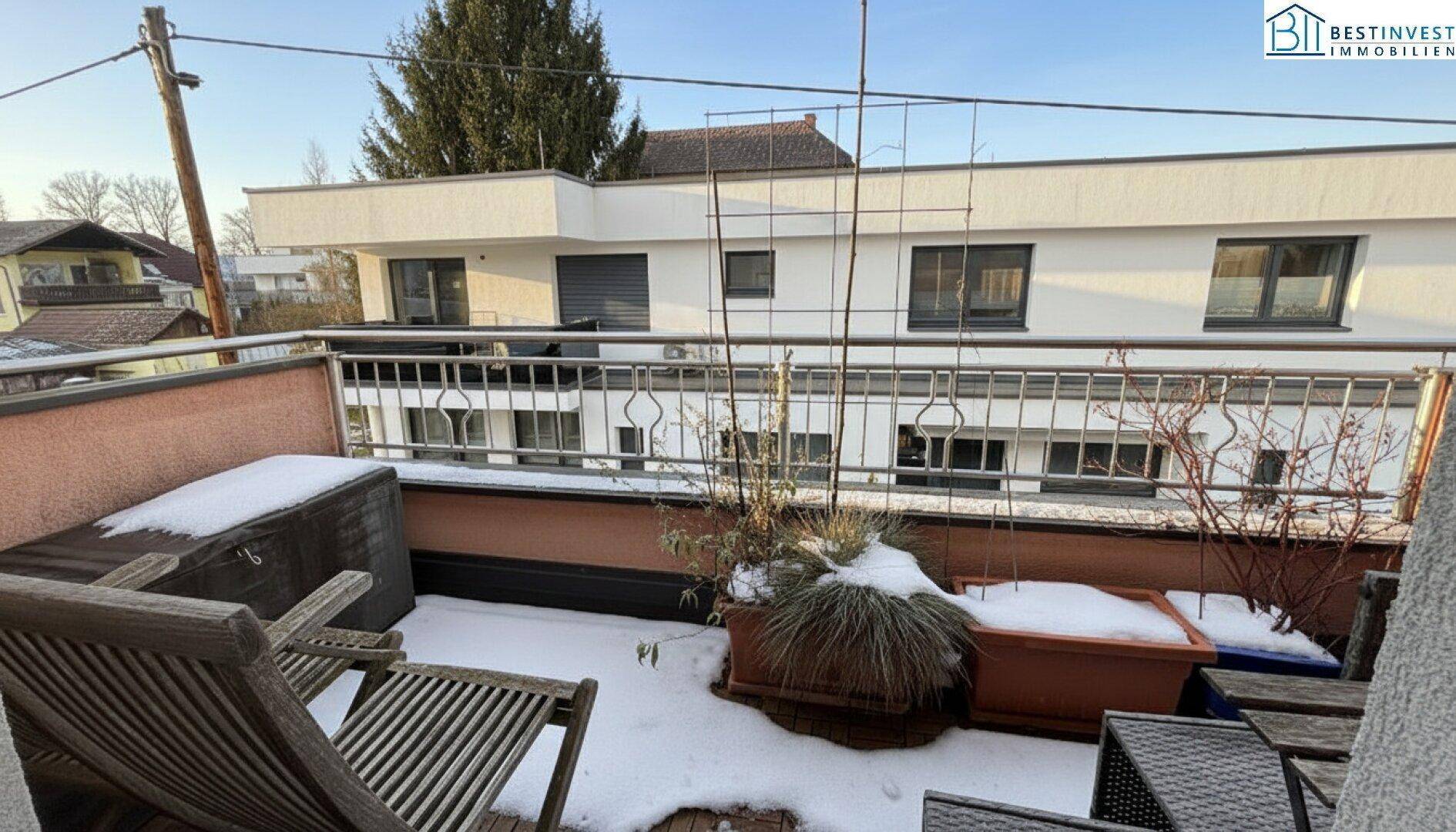 Balkon mit Sitzgelegenheiten und Blick auf die umliegenden Gebäude, teilweise verschneit.