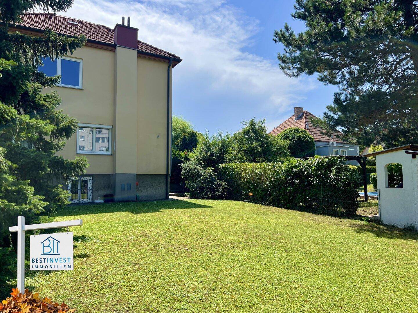Gepflegter Garten mit Rasenfläche und Hecke, angrenzend an die Rückseite des Wohnhauses.