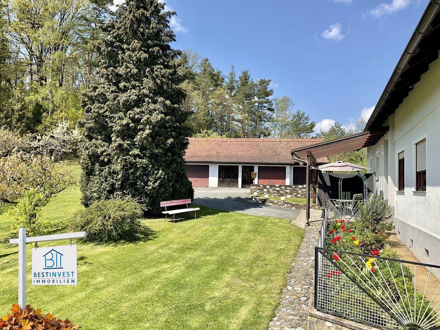Gepflegter Gartenbereich mit Rasenfläche, einem Weg und einer Garage im Hintergrund.