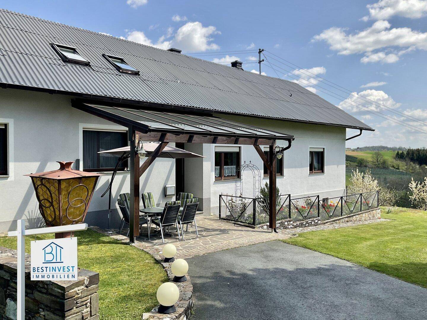 Überdachte Terrasse mit Gartenmöbeln und Blick auf die umliegende Landschaft.