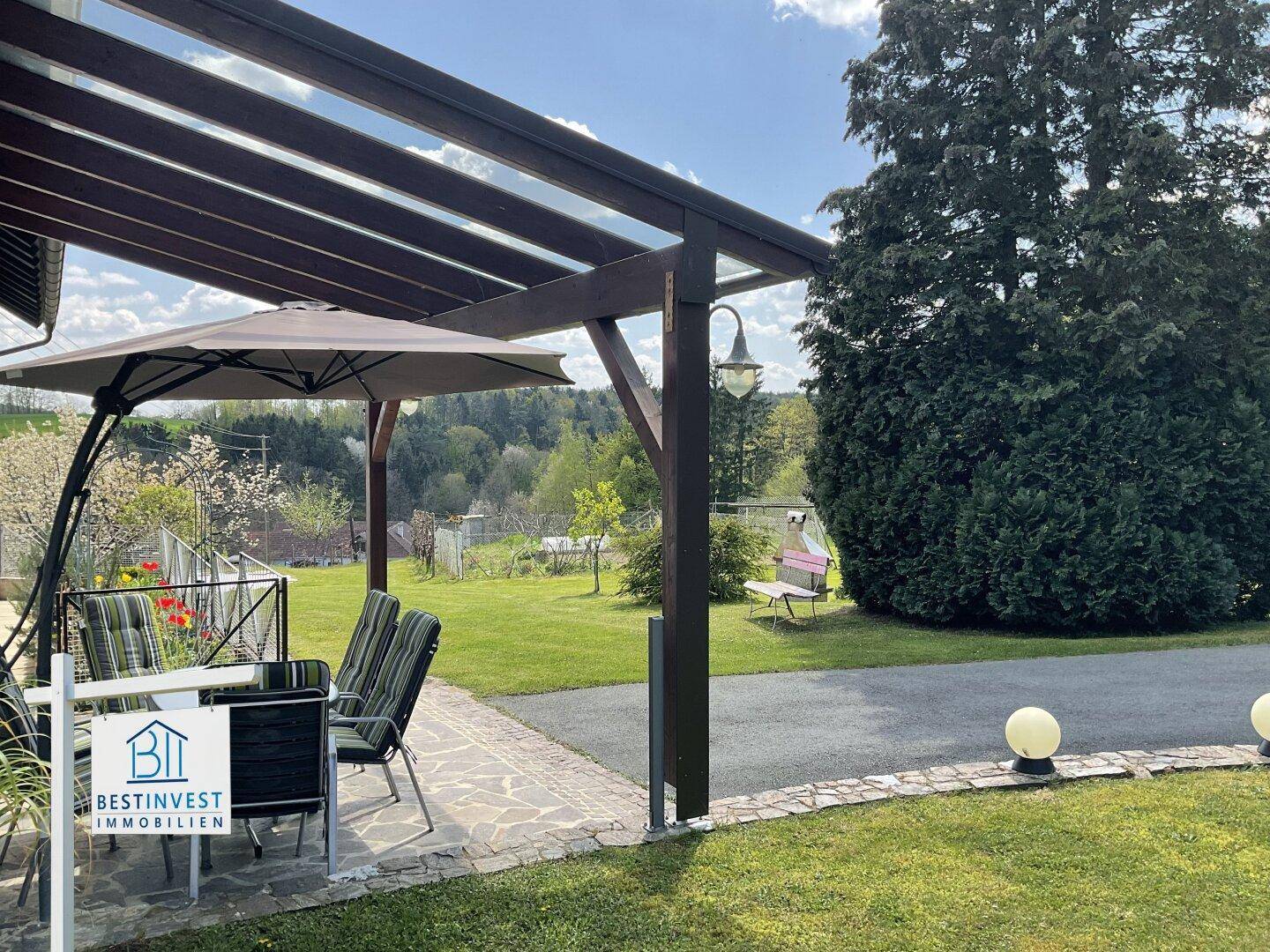 Detailansicht der überdachten Terrasse mit Sitzgelegenheiten und weitem Blick ins Grüne.