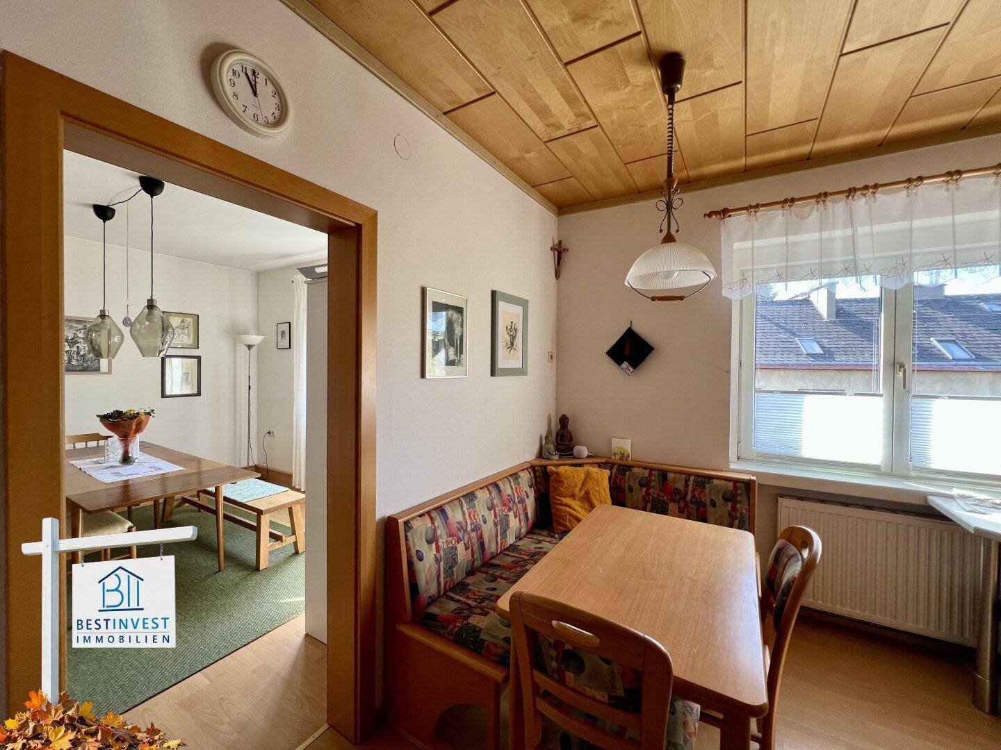Gemütliche Wohnküche mit Holztäfelung an der Decke und traditioneller Sitzecke.
