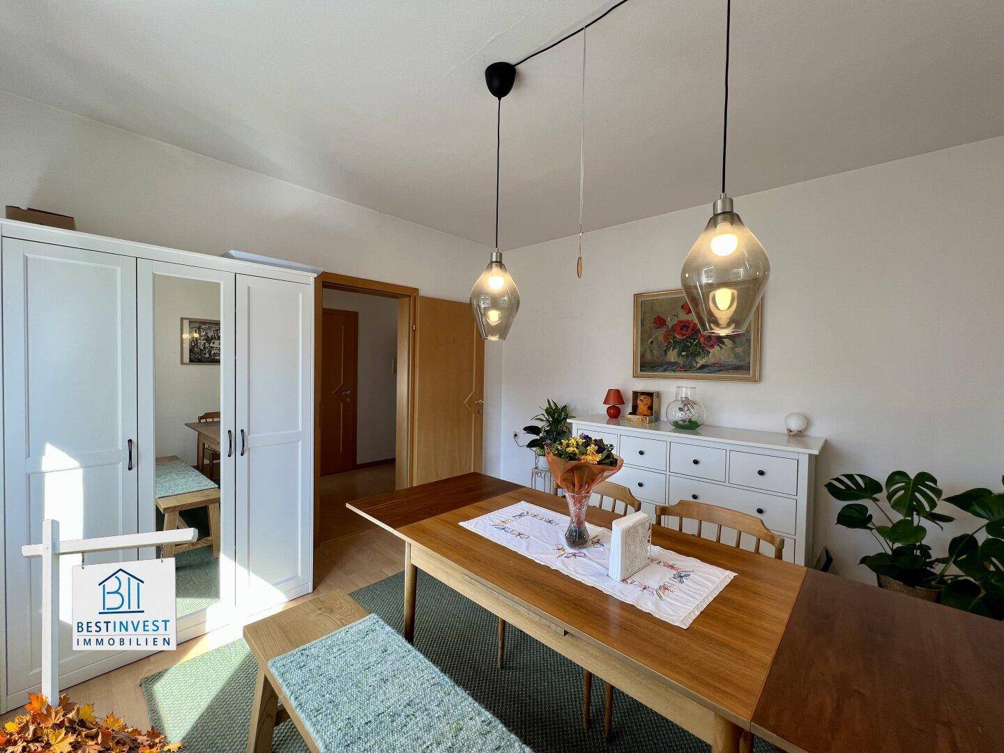 Geräumiger Essbereich mit Holztisch, Sitzbank und weißem Kleiderschrank, offen zum Flur.