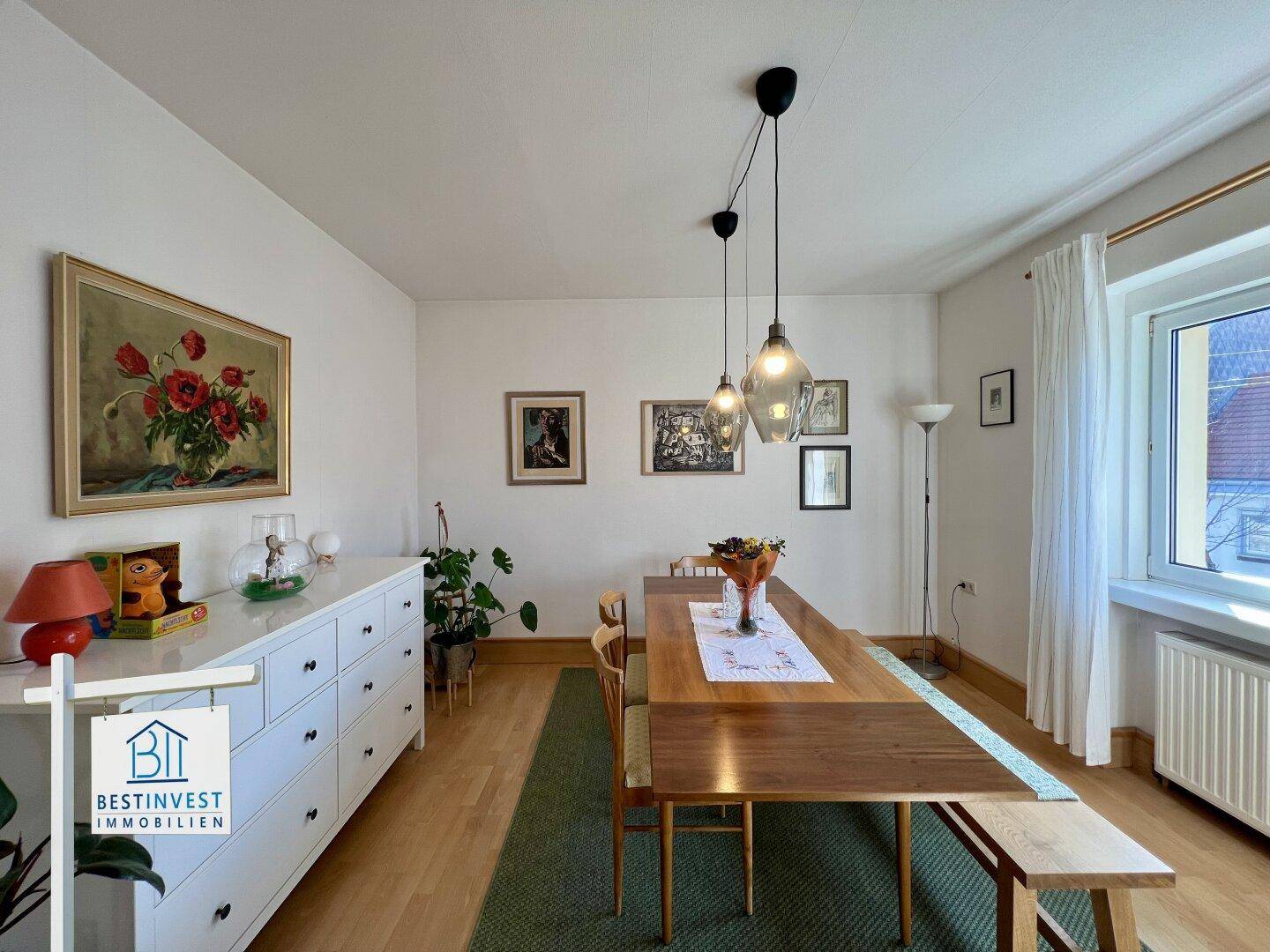 Langer Esstisch in einem hellen Raum mit Holzboden und dekorativen Bildern an der Wand.