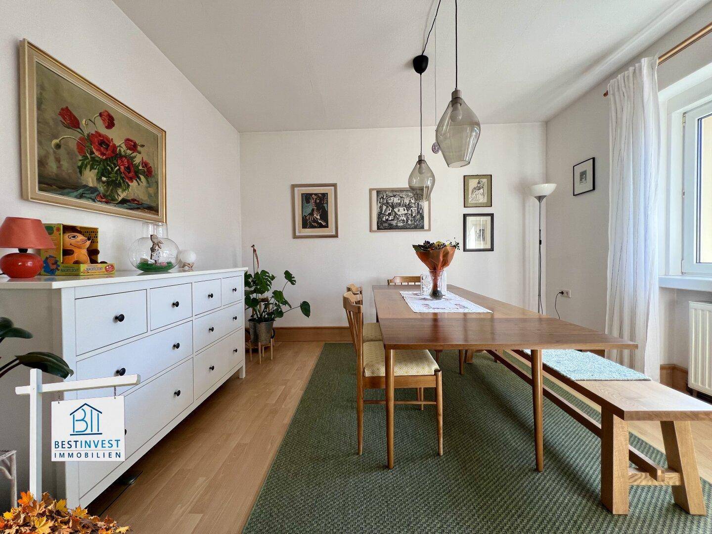 Einladender Essbereich mit Holztisch, Stühlen und einer Bank, umgeben von Kunstwerken.