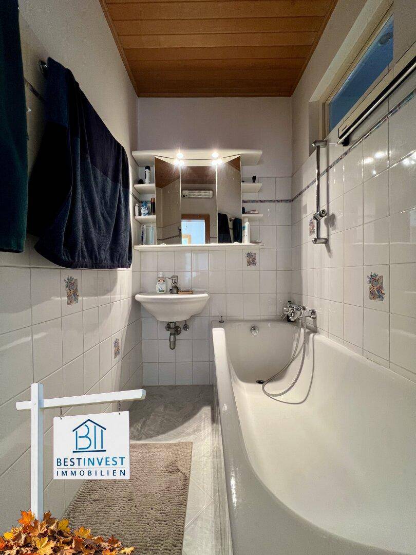Klassisches Badezimmer mit Badewanne, Waschbecken und weißen Fliesen im Retro-Stil.