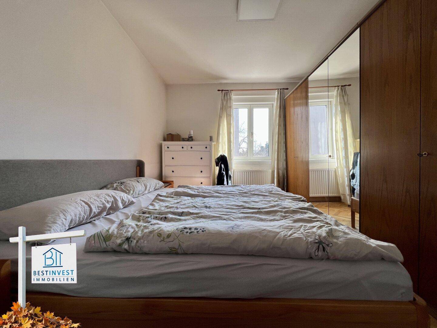 Helles Schlafzimmer mit Doppelbett, großem Spiegelschrank und Fenster mit Ausblick.