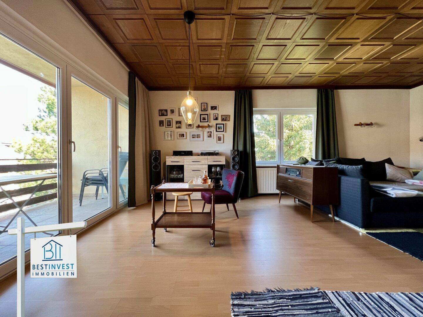 Helles Wohnzimmer mit Balkonzugang, Holzboden und gemütlicher Einrichtung.