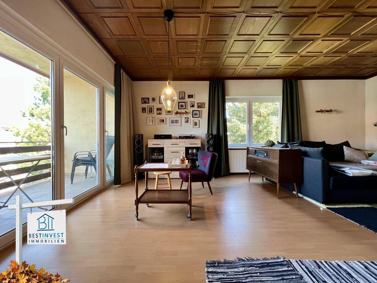 Helles Wohnzimmer mit Holzboden, gemütlicher Sitzecke und Schiebetür zum Balkon.
