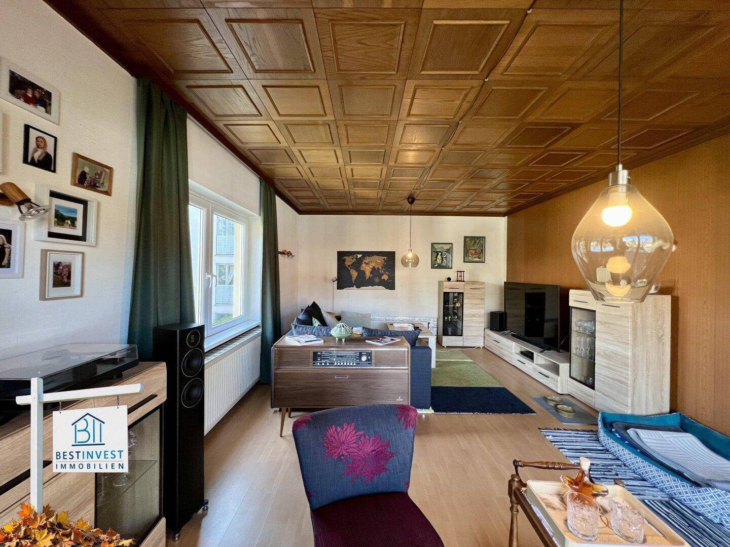 Gemütliches Wohnzimmer mit Holzboden, Fernseher und Blick auf den Garten.