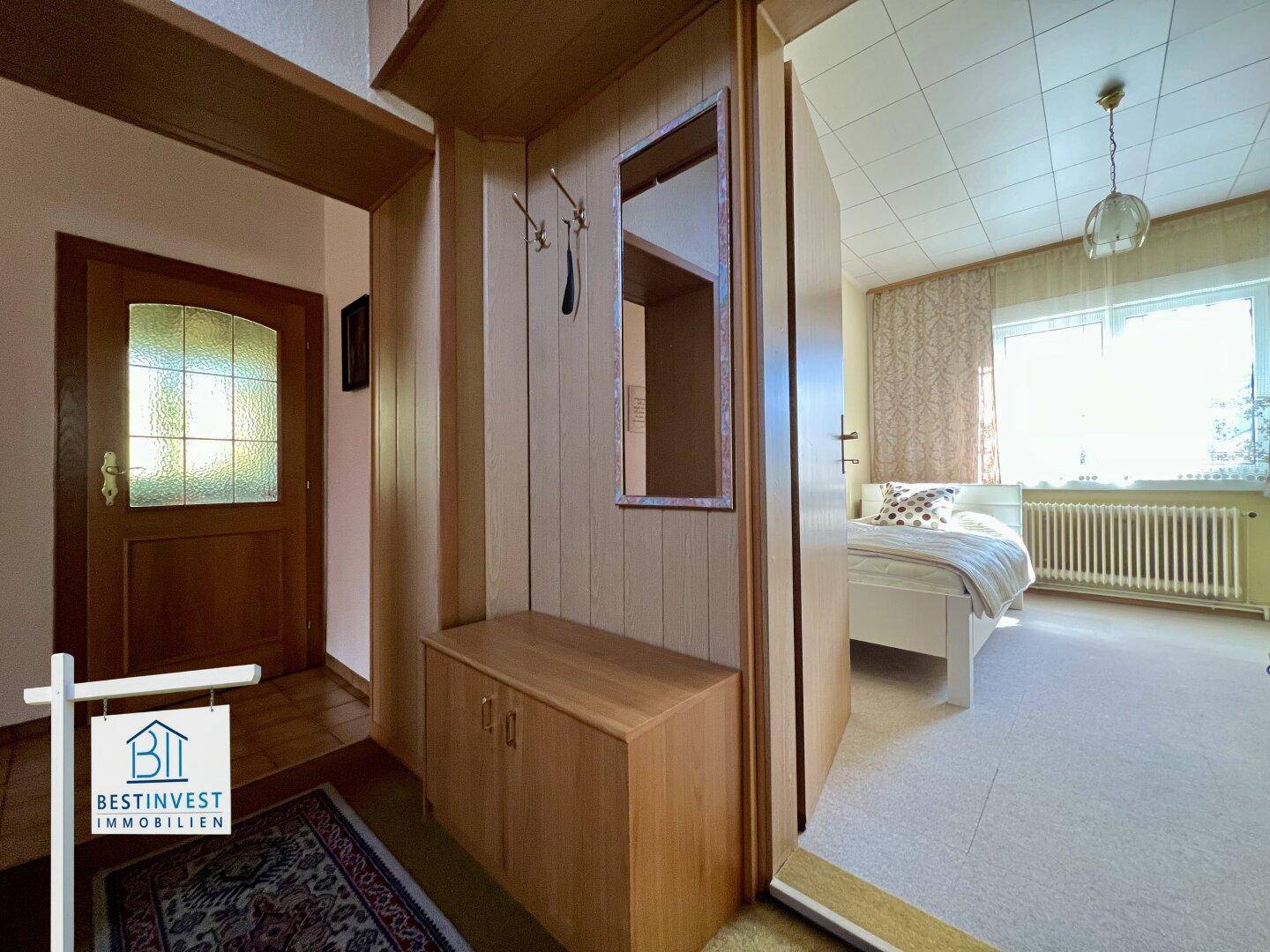 Eingangsbereich mit Garderobe, Holzvertäfelung und Zugang zu einem Schlafzimmer.