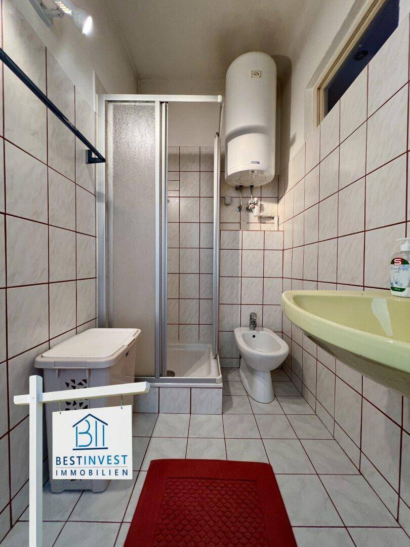 Badezimmer mit Dusche, Bidet und Waschbecken in einem gefliesten Raum.