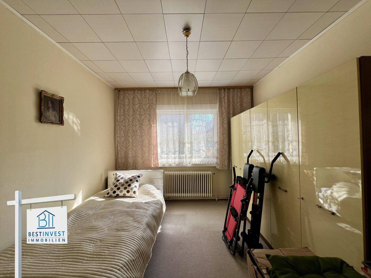 Schlafzimmer mit Einzelbett, Schrank und Fenster für ausreichend Tageslicht.