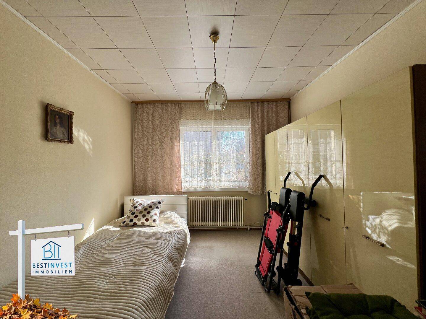 Helles Schlafzimmer mit Einzelbett, großem Kleiderschrank und Fenster.