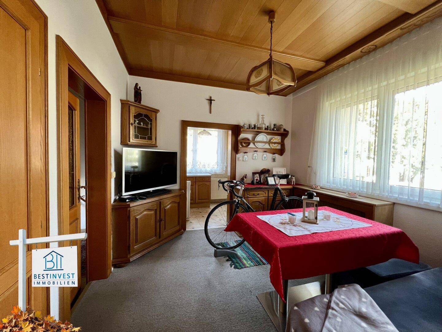 Wohnzimmer mit Holztäfelung, Esstisch und Fernseher, hell und einladend.