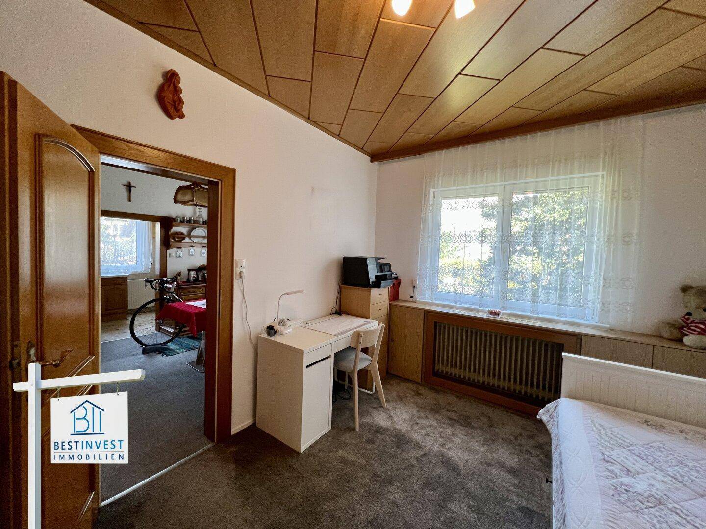 Helles Arbeitszimmer mit Schreibtisch, Bett und Blick ins Grüne durch das Fenster.