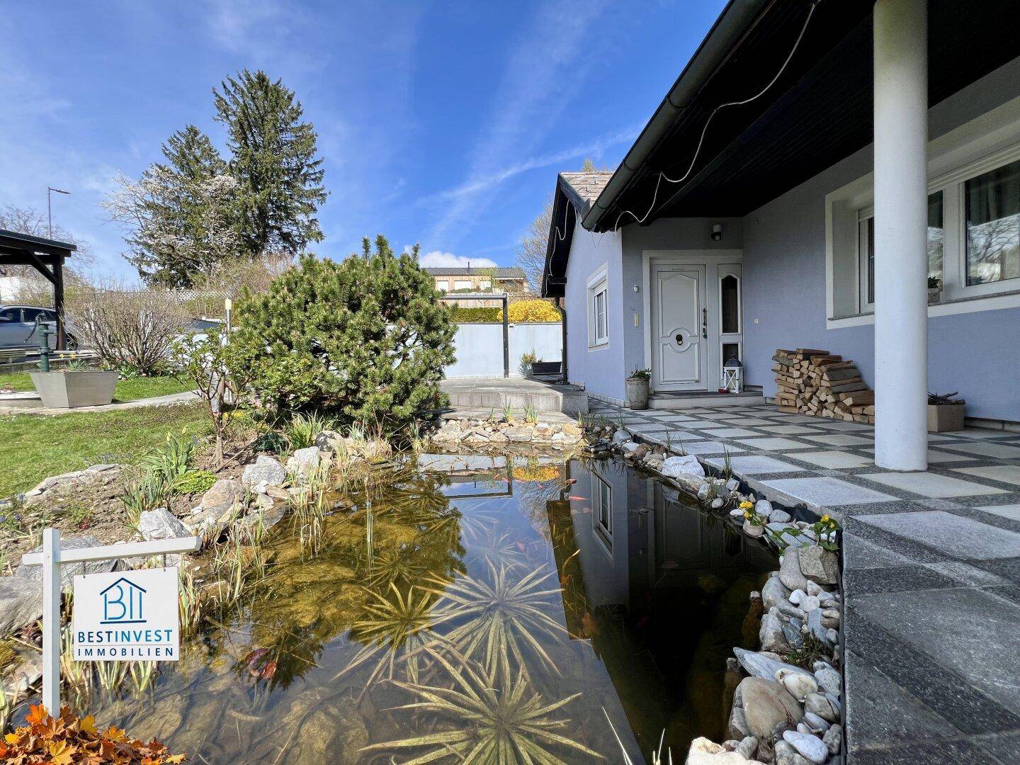 Eingangsbereich des Hauses mit gepflasterter Terrasse und einem dekorativen Teich im Vorgarten.
