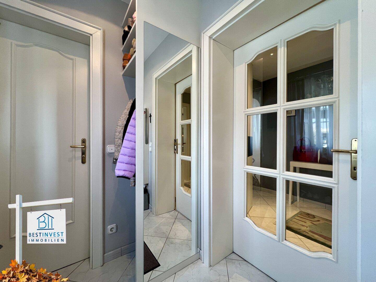 Heller Flur mit Spiegeltür und Garderobenbereich, der zu weiteren Räumen im Haus führt.